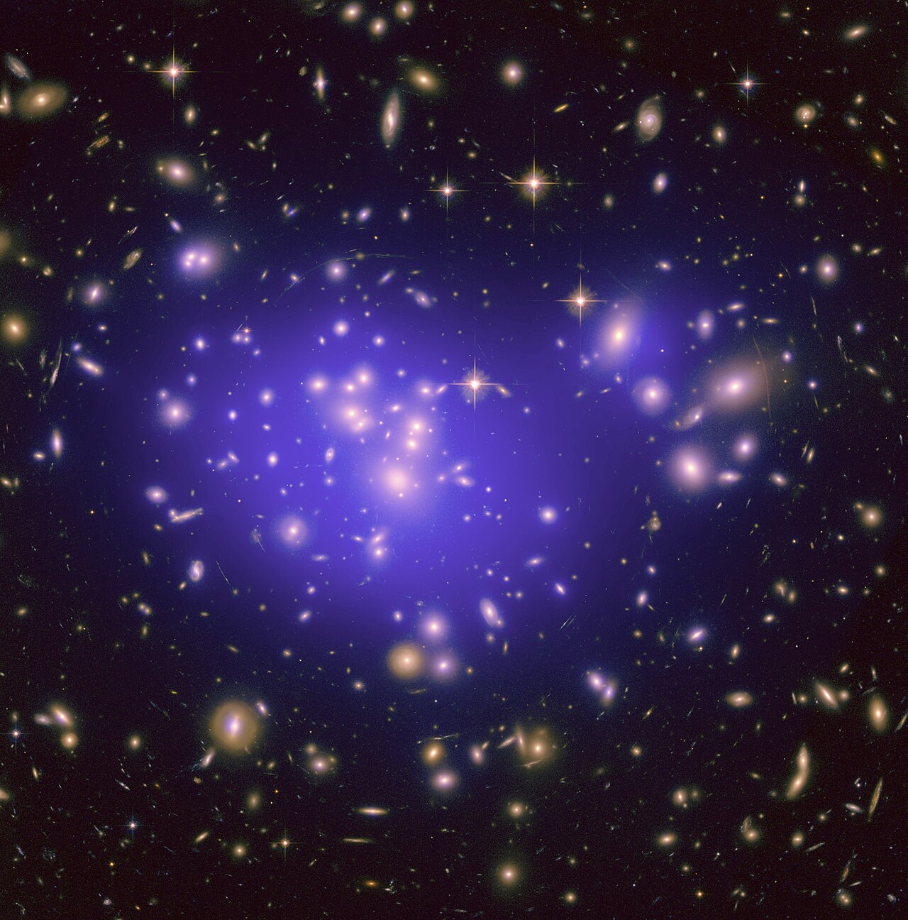 A dense field of galaxies threaded with many faint, thin curved arcs of light.